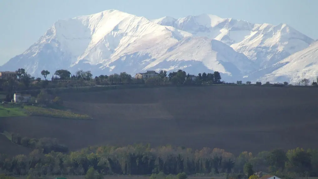 I Monti Sibillini innevati sopra le colline coltivate
