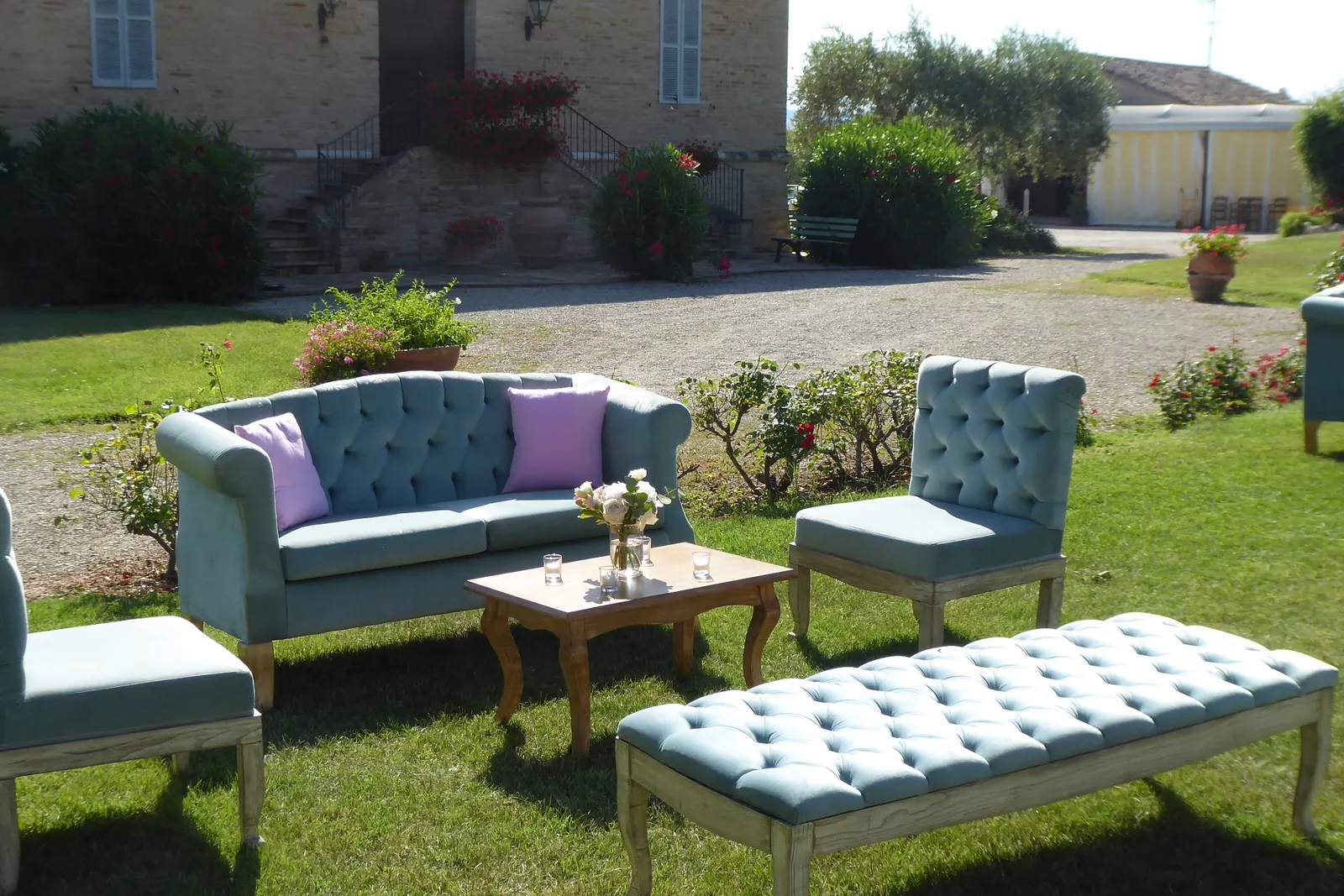 Un salotto di divani in velluto azzurro allestito sul prato davanti alla villa
